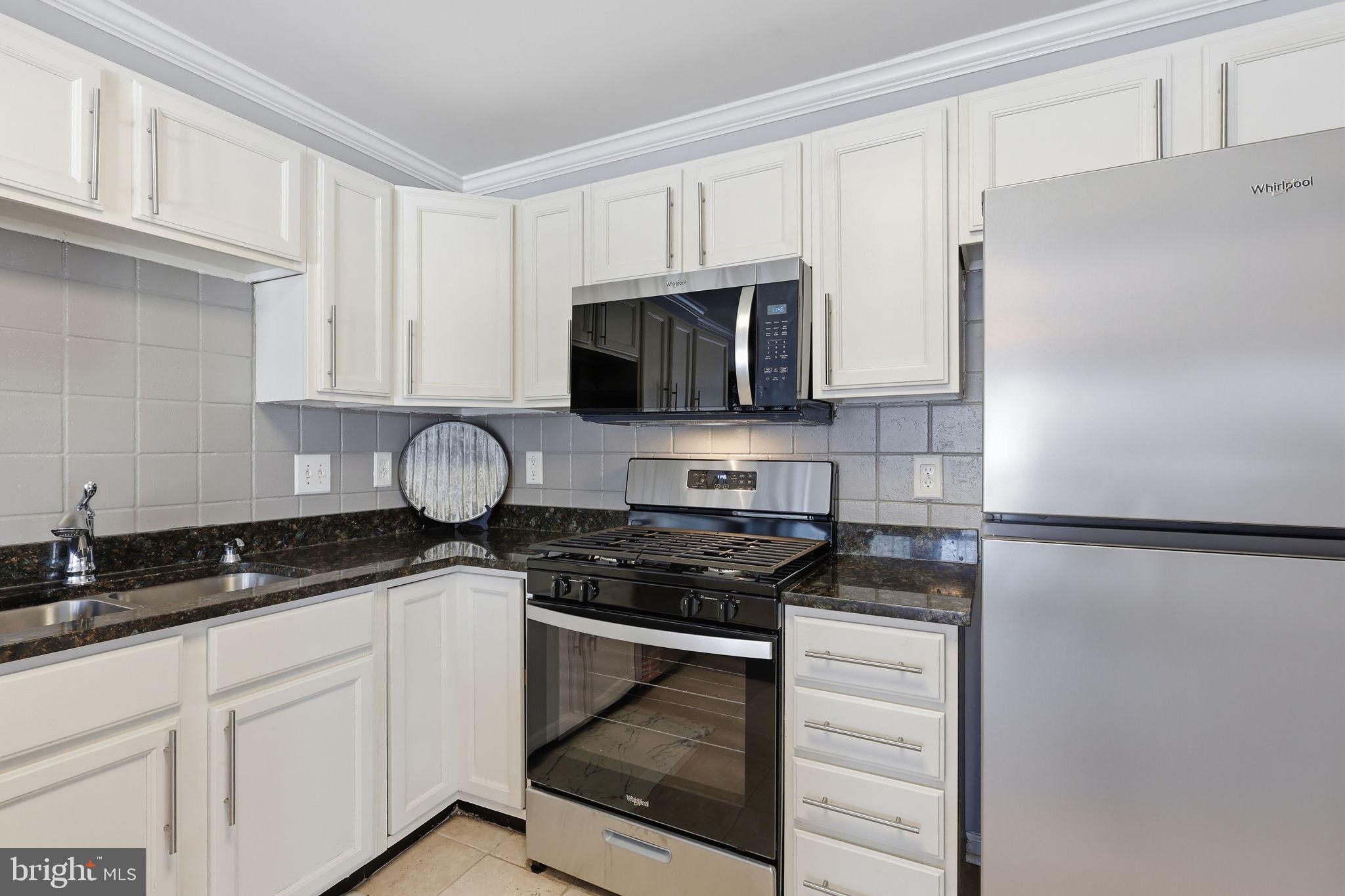 9332 Wax Myrtle Way Manassas, VA 20110 - Photo 2 of 40 a kitchen with granite countertop white cabinets and refrigerator stove