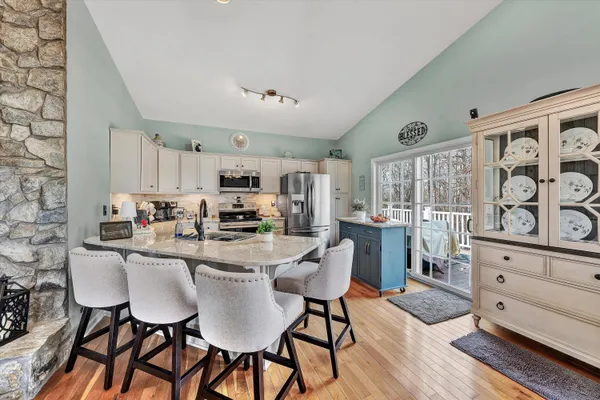 a kitchen with stainless steel appliances kitchen island granite countertop a dining table chairs and white cabinets