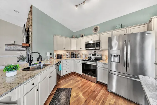 a kitchen with granite countertop stainless steel appliances a sink a counter top space cabinets and stainless steel appliances