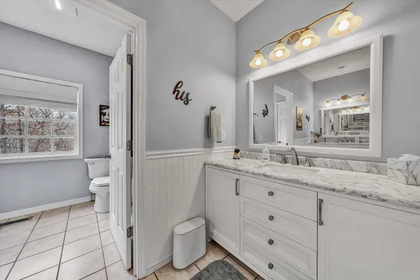 a bathroom with a granite countertop toilet sink and mirror