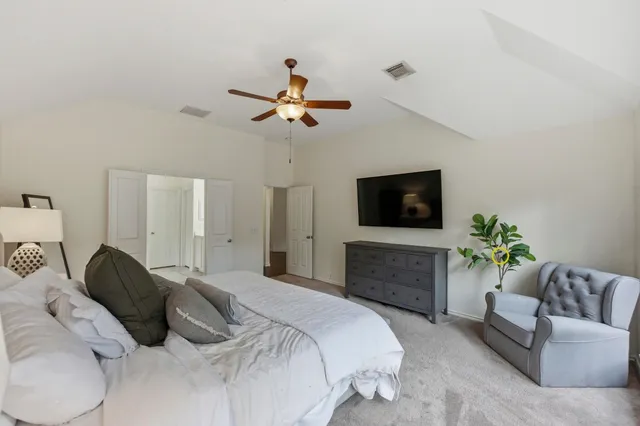 a bedroom with a bed a couch and a flat screen tv