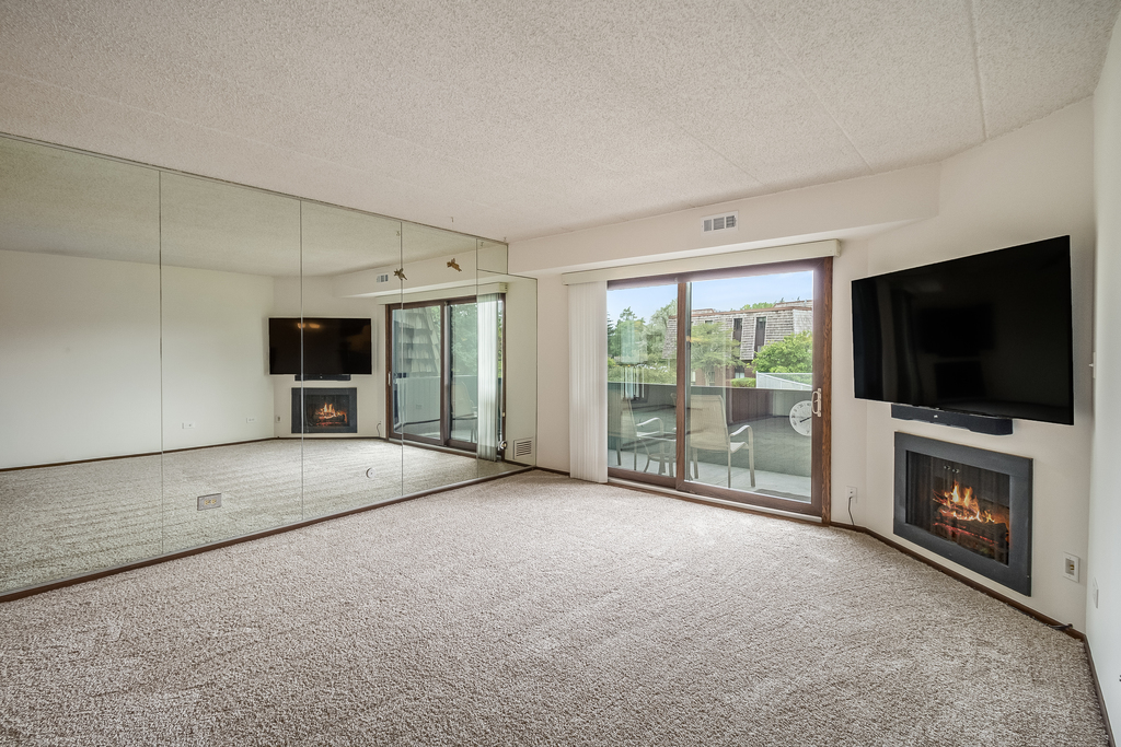 516 Timber Ridge Drive, Unit 206B Carol Stream, IL 60188 - Photo 14 of 20 a view of an empty room with a flat screen tv and a fireplace