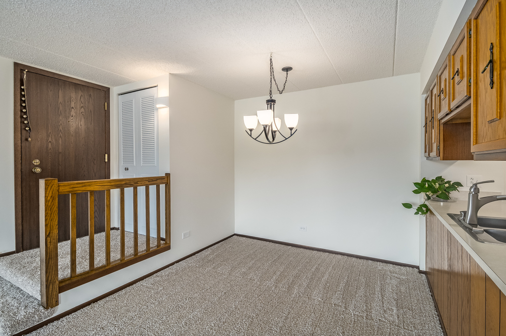 516 Timber Ridge Drive, Unit 206B Carol Stream, IL 60188 - Photo 6 of 20 a view of a hallway to a bedroom with wooden floor and stairs