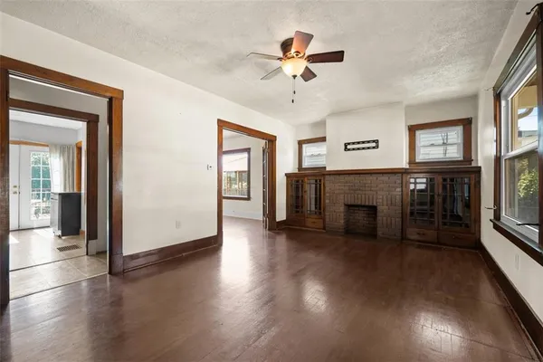a view of a livingroom with wooden floor a ceiling fan and windows
