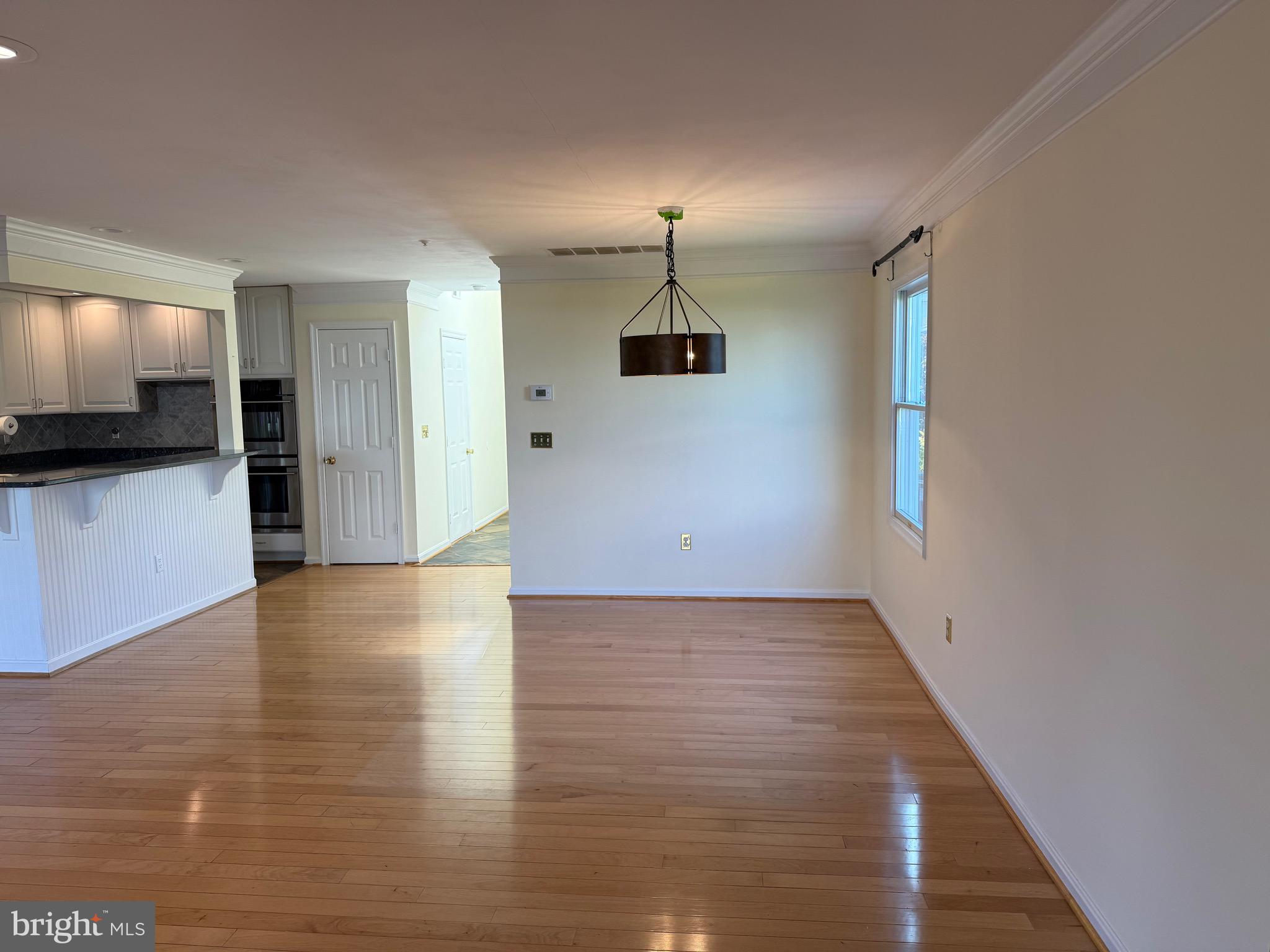 807 Auckland Way Chester, MD 21619 - Photo 13 of 42 a view of a hallway to an empty room with wooden floor and a kitchen