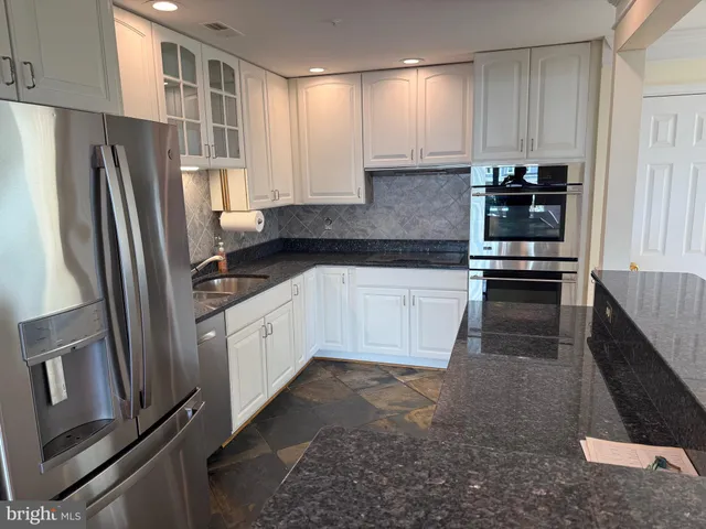 a kitchen with granite countertop a refrigerator sink and cabinets