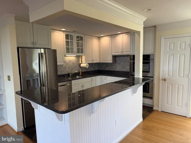 a kitchen with stainless steel appliances granite countertop a refrigerator a sink and a stove