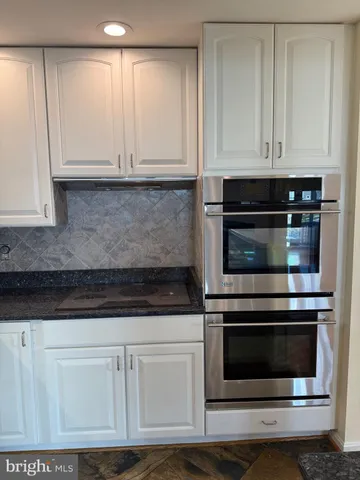 a kitchen with white cabinets and appliances