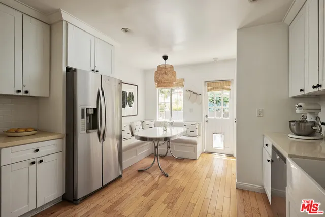 a kitchen with stainless steel appliances a refrigerator a stove a sink and white cabinets with wooden floor