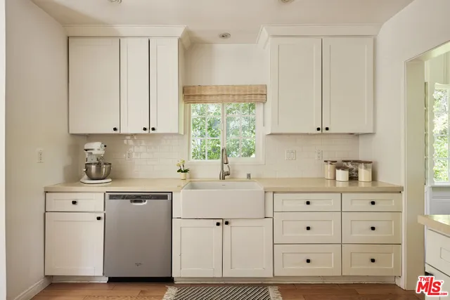 a kitchen with white cabinets and a window