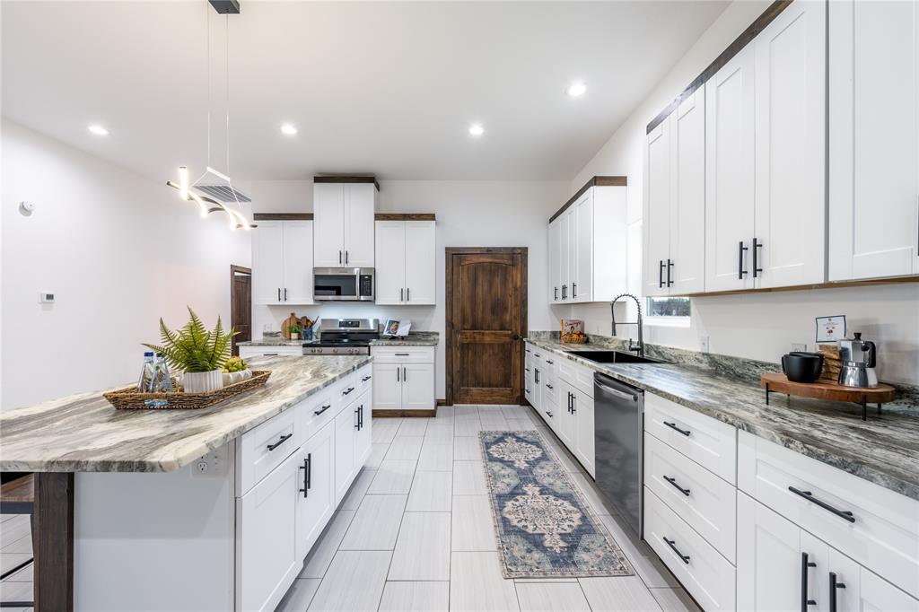 1706 County Road Sumner, TX 75486 - Photo 12 of 28 a kitchen with granite countertop kitchen island white cabinets and white appliances