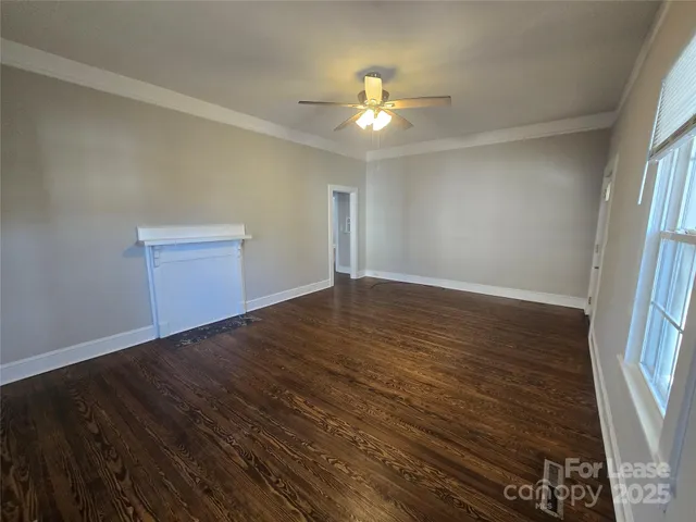 an empty room with wooden floor chandelier fan and windows