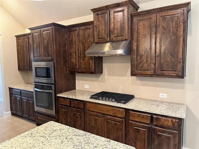 a kitchen with stainless steel appliances granite countertop a refrigerator and a stove top oven
