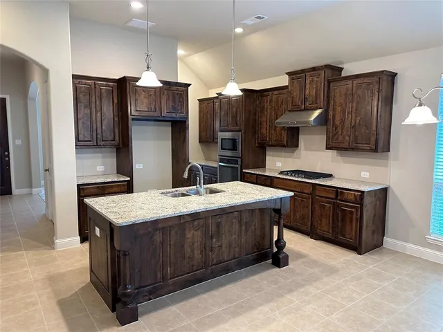 a kitchen with stainless steel appliances granite countertop a stove a refrigerator and a sink