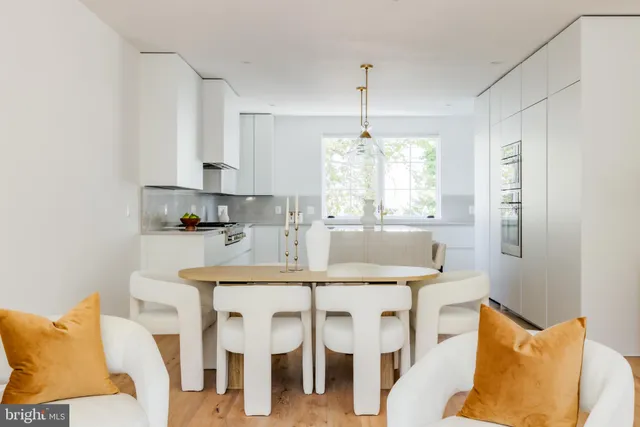 a kitchen with stainless steel appliances kitchen island granite countertop a dining table chairs and white cabinets