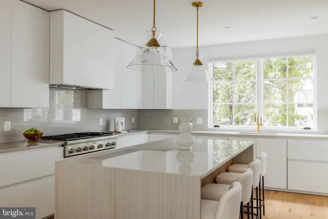 a kitchen with stainless steel appliances granite countertop a stove a sink and white cabinets with wooden floor