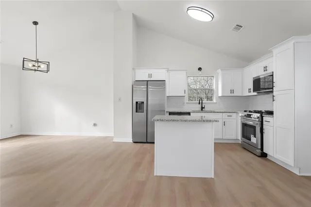 a kitchen with kitchen island white cabinets and stainless steel appliances