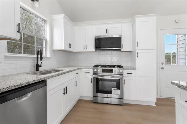 a kitchen with stainless steel appliances granite countertop a sink stove and microwave