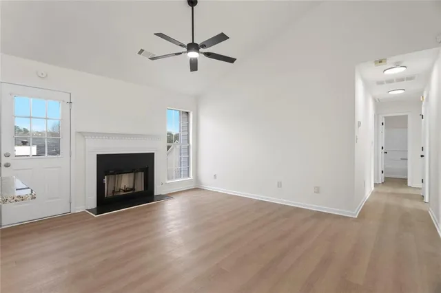 a view of an empty room with wooden floor fireplace and a window