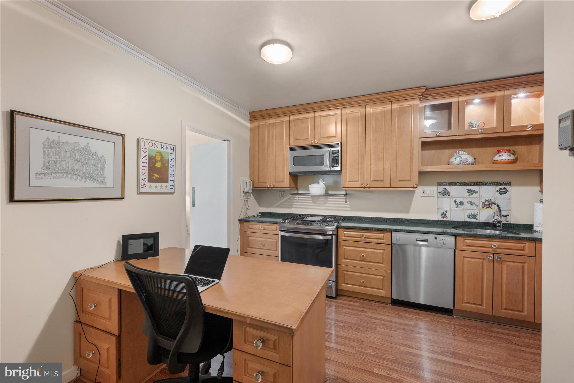 4100 Cathedral Avenue Northwest, Unit 717 Washington, DC 20016 - Photo 18 of 34 a kitchen with stainless steel appliances granite countertop a stove top oven a sink dishwasher and cabinets with wooden floor