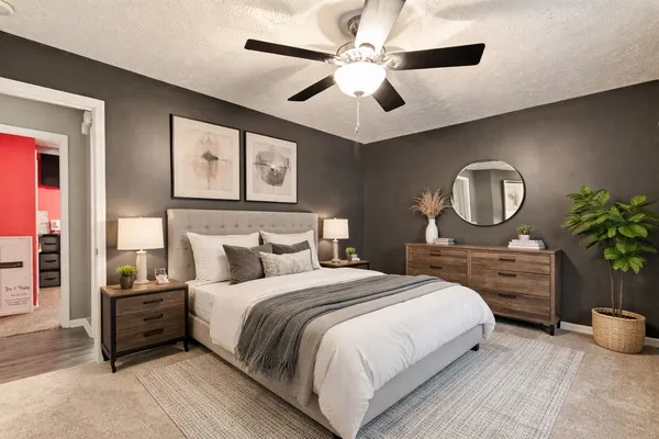 a bedroom with a bed a ceiling fan and a potted plant