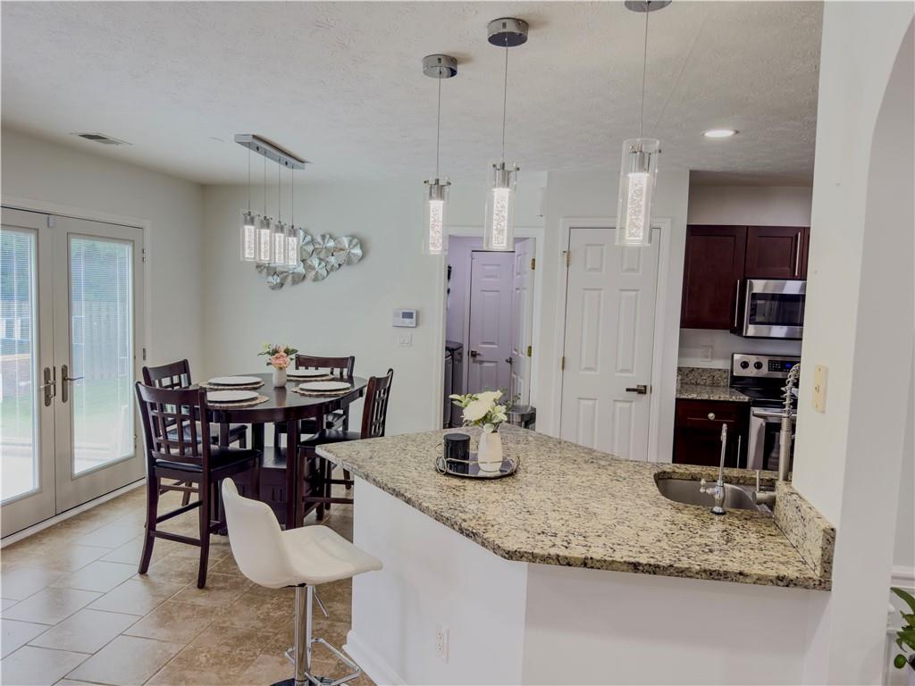 1559 Woodmore Road Southwest Marietta, GA 30008 - Photo 14 of 43 a kitchen with stainless steel appliances kitchen island granite countertop a dining table chairs and a refrigerator