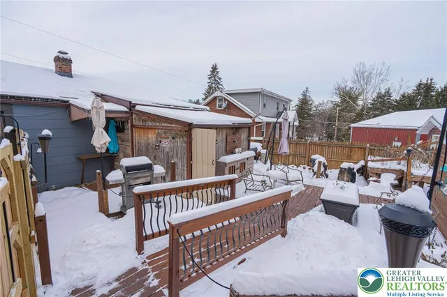a view of a roof deck with table and chairs a barbeque with wooden floor and fence