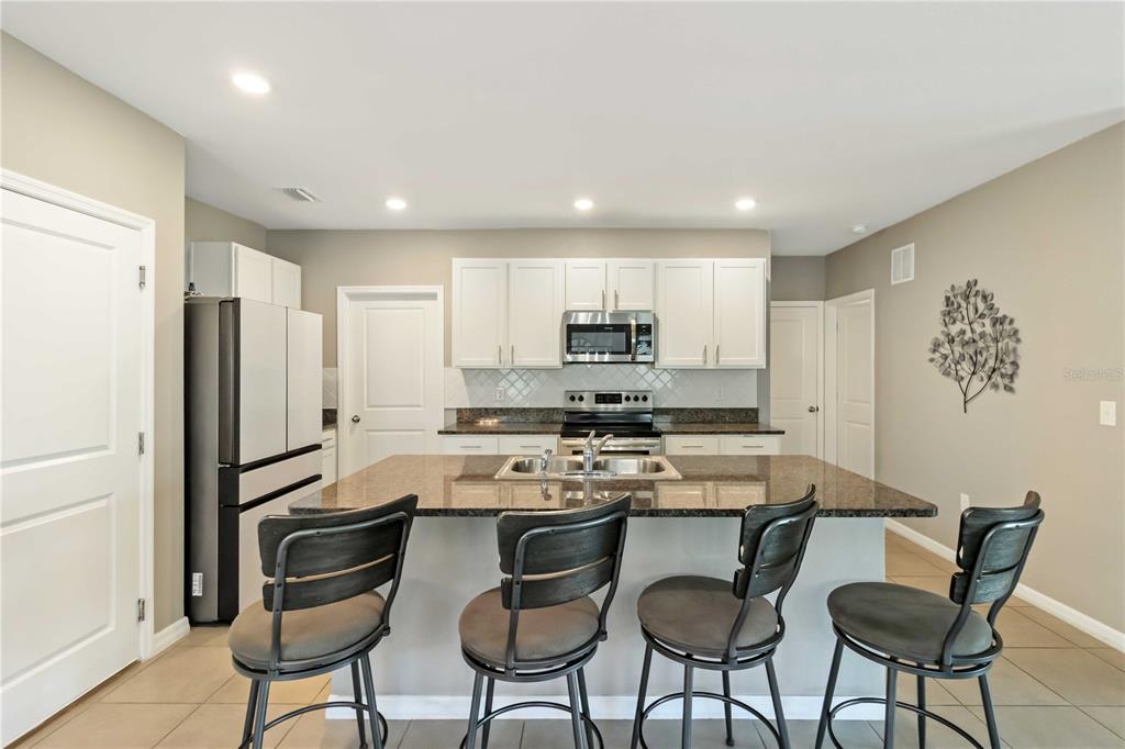 5904 Silver Sage Way Sarasota, FL 34232 - Photo 16 of 43 a kitchen with stainless steel appliances a stove a refrigerator sink and white cabinets with wooden floor