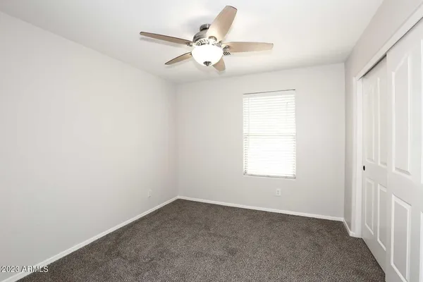 an empty room with a window and a fan