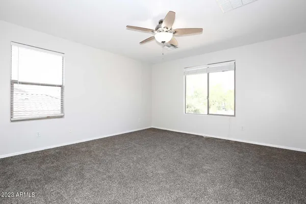 an empty room with windows and fan