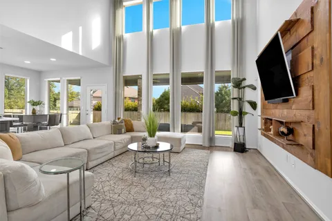 a living room with furniture a flat screen tv and a floor to ceiling window