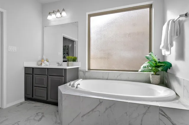 a white bath tub sitting in a bathroom next to a window