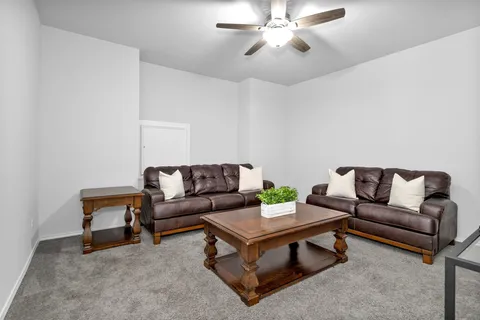 a living room with furniture and a ceiling fan