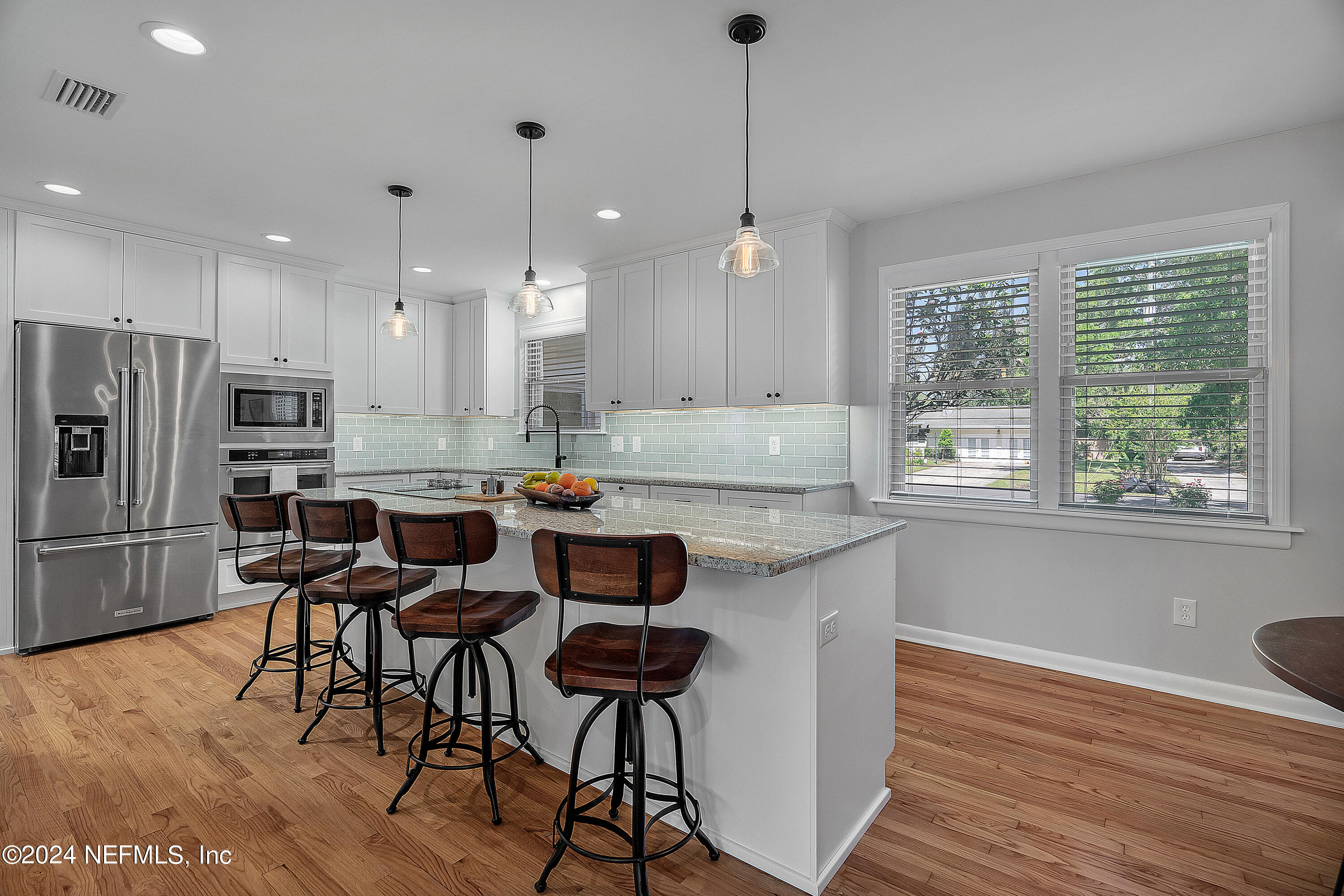 4724 Devon Lane Jacksonville, FL 32210 - Photo 8 of 40 a kitchen with stainless steel appliances kitchen island granite countertop a refrigerator a stove a sink and chairs with wooden floor