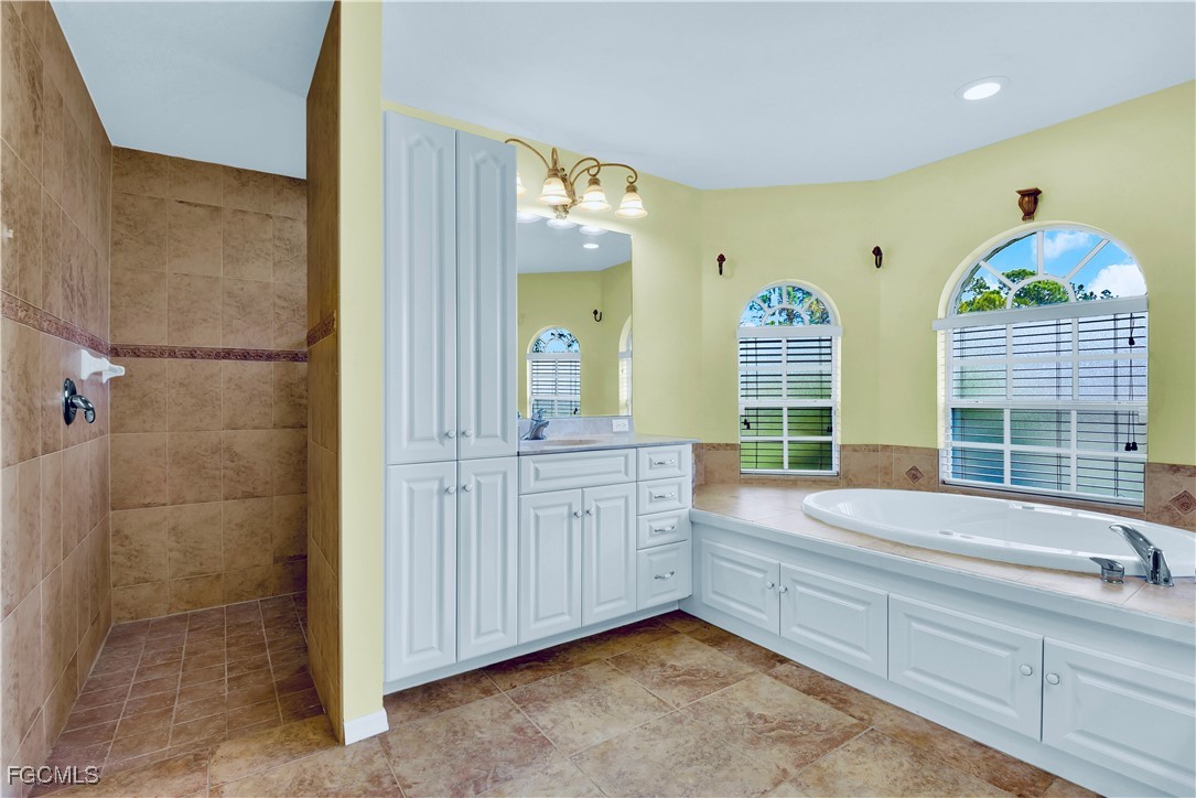909 Magnolia Avenue Lehigh Acres, FL 33972 - Photo 13 of 38 a bathroom with a tub sink and mirror