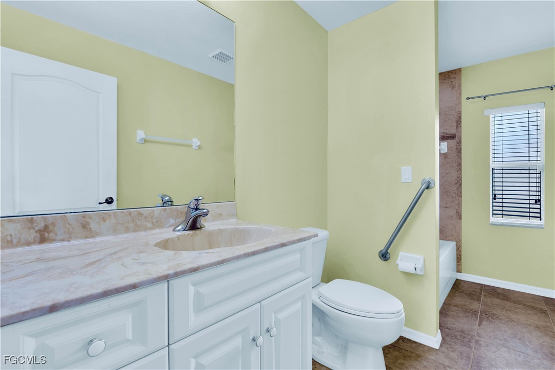 909 Magnolia Avenue Lehigh Acres, FL 33972 - Photo 27 of 38 a bathroom with a sink a toilet and a mirror