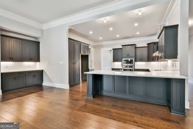 a kitchen with kitchen island granite countertop a sink cabinets and stainless steel appliances