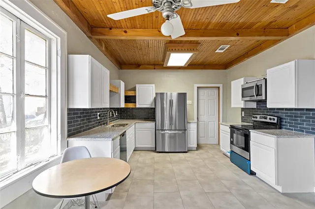 a kitchen with stainless steel appliances granite countertop a stove a refrigerator a sink a oven with a dining table and chairs