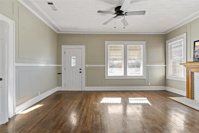 a view of empty room with wooden floor and fan