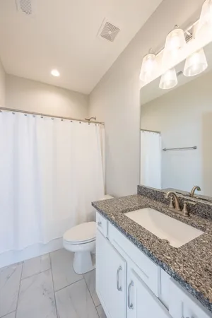 a bathroom with a granite countertop sink a toilet and a mirror