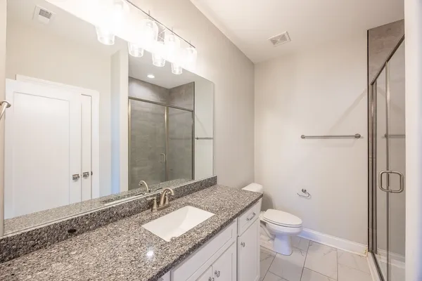 a bathroom with a granite countertop sink mirror vanity and toilet