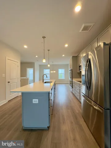 a kitchen with stainless steel appliances granite countertop a refrigerator a stove a sink dishwasher and a refrigerator with wooden floor