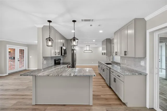 a large kitchen with granite countertop cabinets a sink a window and stainless steel appliances