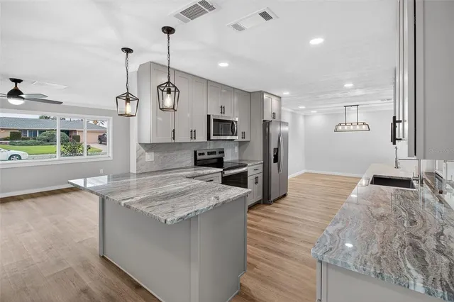 a large kitchen with kitchen island a stove a sink dishwasher and a oven with wooden floor