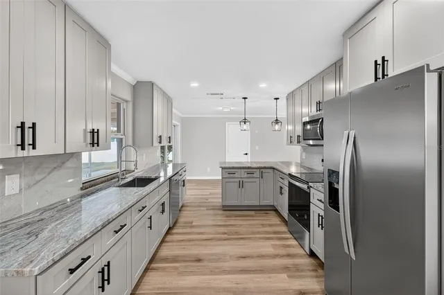 a large kitchen with stainless steel appliances lots of counter space and wooden floor