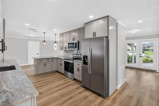 a large kitchen with a center island wooden floor stainless steel appliances and windows