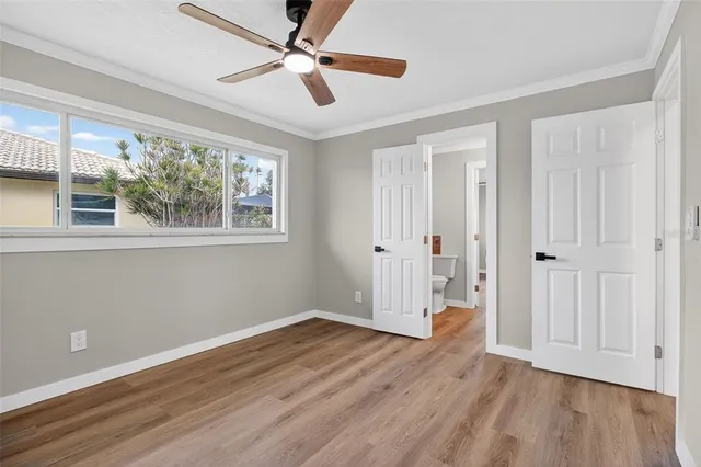 an empty room with wooden floor chandelier fan and windows