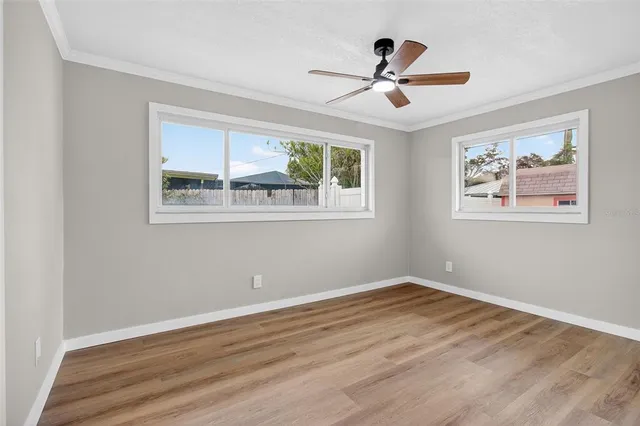 a view of empty room with wooden floor and fan