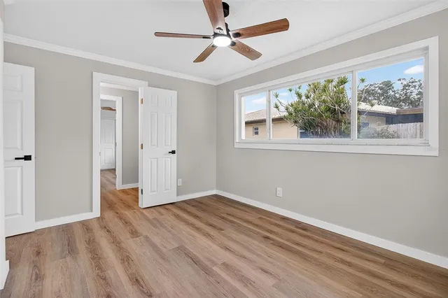 a view of empty room with wooden floor and fan