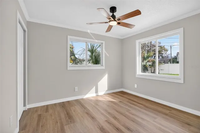 a view of empty room with wooden floor and fan